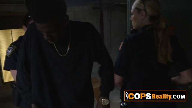 Apprehended black suspect is getting his cock sucked hard by two horny MILF cops in uniforms.