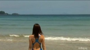 Teen Japanese sea in a blue bathing suit floating on the shore