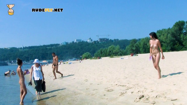 An adorable nudist girls strolls around on the beach and lies down naked