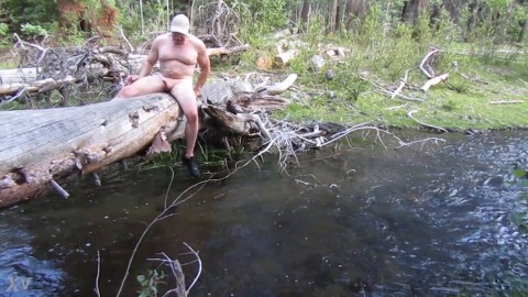 Naked on a log and in the stream.