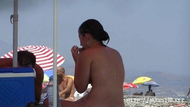 Nudist video at the beach has shy girl playing in the water
